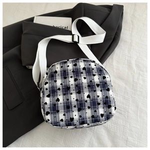 Detail of blue and white checkered crossbody bag with black heart prints and adjustable strap