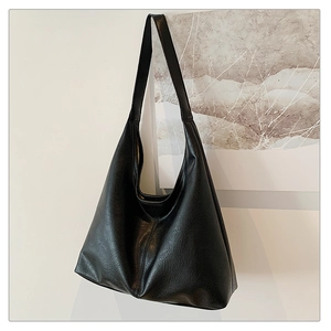 Detail of minimalist black oversized hobo bag showing soft leather texture and wide strap
