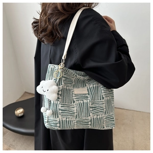 Detail of green and white striped canvas tote bag with cute cloud charm and leather straps