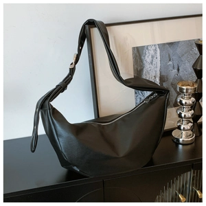 Detailed close-up of matte black leather croissant bag with silver zipper and wide strap