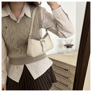 Detail view of the cream underarm bag with decorative buckle and slim shoulder strap