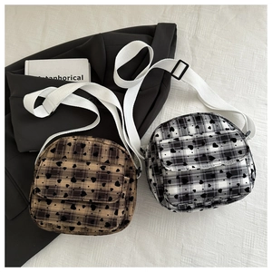 Detailed flat lay of mini plaid crossbody bags with heart prints and adjustable straps