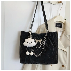 Detail of black pleated tote bag featuring silver chains and a plush cloud charm