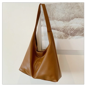 Detail showing the natural leather texture of a brown hobo bag with a minimalist design