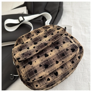 Detail of checkered crossbody bag with black heart embroidery and adjustable woven strap