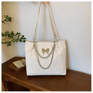 Close-up of silver tote bag featuring butterfly metal charm and pearl chain decoration