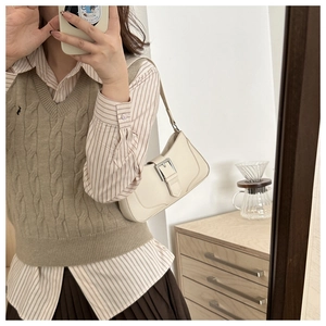 Close-up of cream crescent shoulder bag with silver buckle and matte leather texture