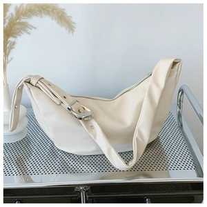 Close-up of beige hobo bag with silver buckle and metal eyelet detail on the shoulder strap