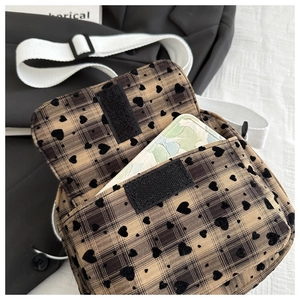 Close-up of checkered mini bag with black flocked hearts and adjustable strap