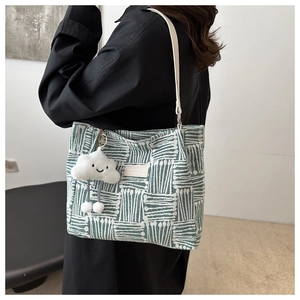 Close-up of green geometric canvas tote featuring a plush cloud charm and leather strap