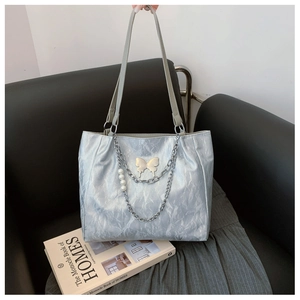 Close-up of metallic tote bag featuring silver butterfly charm and pearl chain details