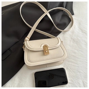 Close-up of cream PU leather crossbody bag with gold snap and smartphone for scale