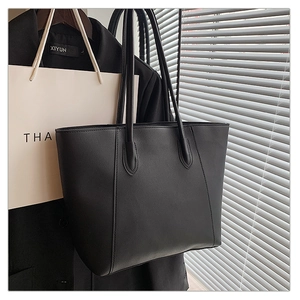 Close-up of a matte black large capacity tote bag with long dual handles in office setting