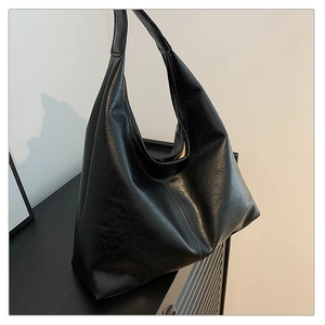 Close-up of black retro tote bag with textured pleated surface on a wooden surface
