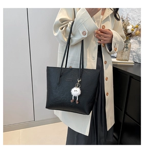 Détail du sac cabas en cuir noir avec motifs gaufrés et breloque en peluche sur mannequin