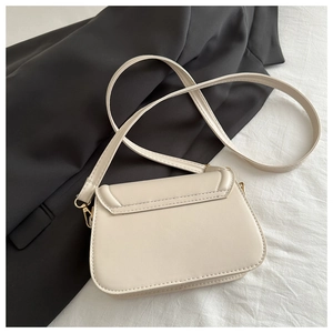 Detail of elegant off-white faux leather shoulder bag with gold metal buckle hardware