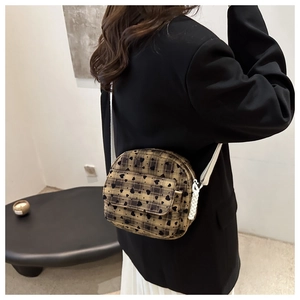 Detail of khaki plaid crossbody bag with black heart patterns and woven strap