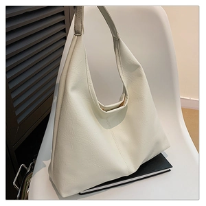 Detail of white pebbled leather hobo bag on chair showing smooth texture and wide strap