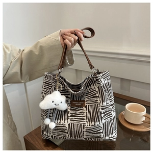 Detail of canvas tote bag with black and white geometric patterns and leather handles