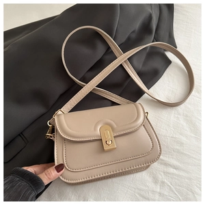 Detail of beige faux leather handbag with elegant gold clasp on black fabric background