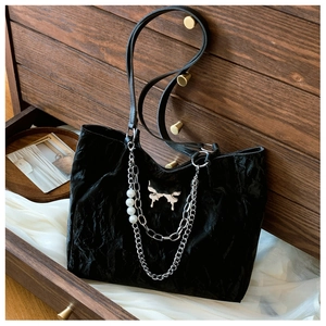 Detail of black pleated tote bag with silver butterfly charm and pearl chain accent