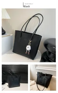 Détail du cabas noir avec motifs de dessins animés gaufrés et charme en peluche