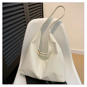 Detail view of large white PU leather tote bag with natural grain texture on a chair