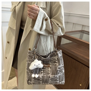 Detail of canvas tote bag with black and white stripes and cute cloud charm accessory