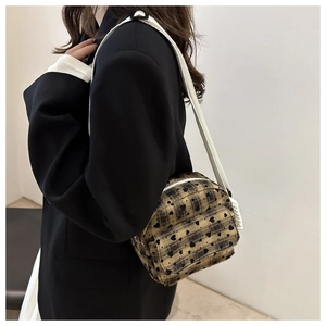 Close-up of a khaki plaid crossbody bag with black heart patterns and white strap on a model