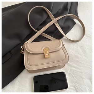 Detail view of beige crossbody bag with gold buckle and smartphone for size reference