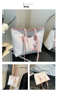 Détail du sac cabas en cuir crème avec bandoulières roses et motifs cœurs et vélos embossés