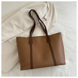 Draufsicht auf einen geräumigen braunen Shopper aus Kunstleder auf einem hellen Sakko