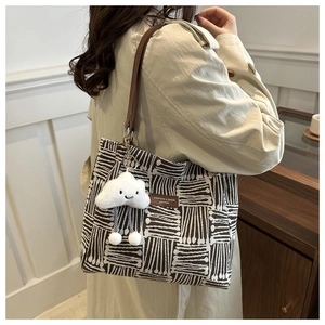 Close-up of geometric canvas tote bag with leather strap and cute cloud charm accessory