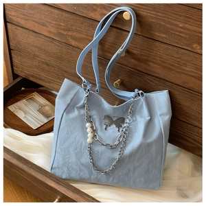 Detail of light blue tote bag with metallic butterfly pendant and pearl chain decoration
