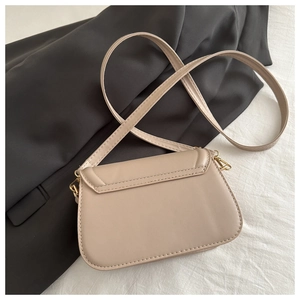 Detail of beige faux leather shoulder bag featuring back pocket and gold metal hooks