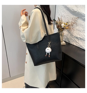 Détail du sac cabas en cuir noir gaufré avec un pendentif en peluche blanche