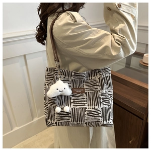 Detail of canvas tote bag with geometric patterns, leather strap, and cloud charm