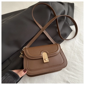 Detail of a brown leather crossbody bag featuring U-shaped stitching and a gold metal clasp