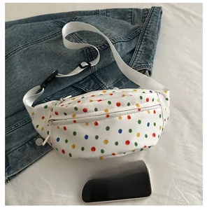 Close-up of a white polka dot canvas waist bag showing zipper and adjustable strap