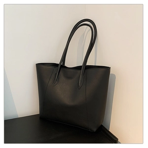 Detail view of large black tote bag with matte PU leather texture and vertical stitching