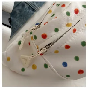 Detail of a white canvas waist bag with colorful dots featuring a smooth dual-zipper system