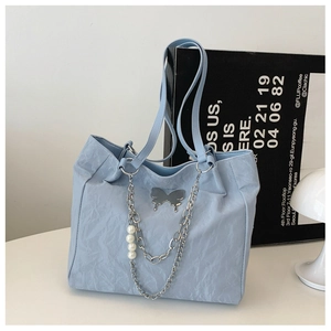 Detailed shot of light blue wrinkled fabric tote bag with silver butterfly and pearl chain