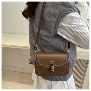 Brown vintage PU leather shoulder bag with gold clasp shown on a model's outfit