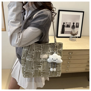 Detail of green woven tote bag with cute cloud plush charm and fashion logo label