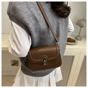 Detail of a vintage dark brown leather crossbody bag featuring a gold metal buckle closure