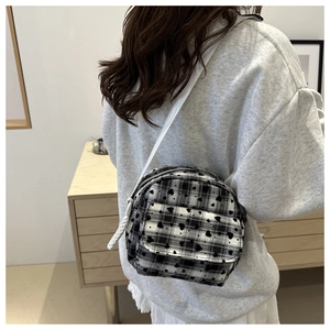 Close-up of heart pattern checkered crossbody bag worn by model in a bright room