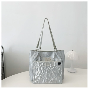 Macro shot of silver metallic tote bag featuring gold butterfly detail and crinkled texture