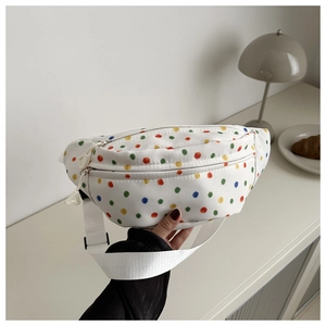 Detailed shot of white canvas fanny pack with colorful polka dots on a cream table