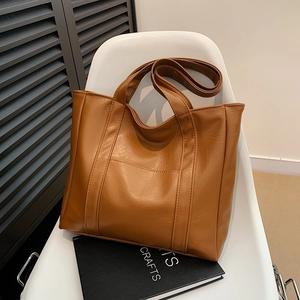 Brown large capacity PU leather tote bag with dual handles on a white chair