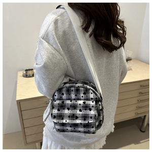 Detailed view of checkered mini crossbody bag with heart patterns on a wide strap